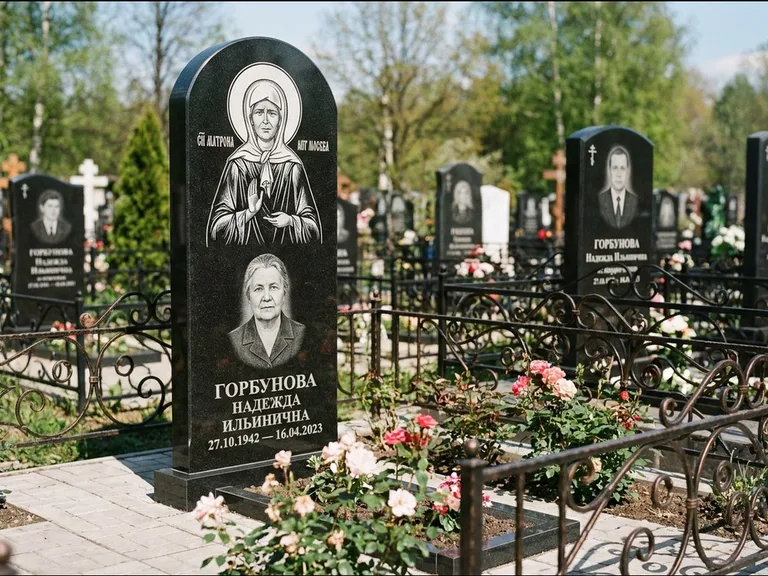 Памятник с гравировкой иконы: стела с арочным верхом и киотом под образ — гравировка образа Матроны Московской, гранитный цоколь с тёмной плиткой, работа «Ковалёв» в Краснодаре