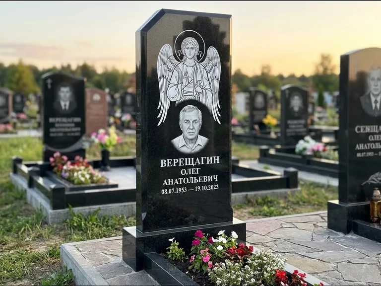 Памятник с гравировкой иконы: стела с резным навершием и нимбом в золоте — гравировка образа Спасителя, высокие разросшиеся туи полукругом, работа «Мельникова» в Краснодаре