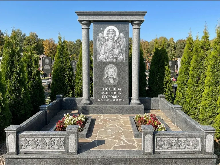 Памятник с гравировкой иконы: массивная стела с двускатным навершием-домиком — гравировка Николая Чудотворца, живая изгородь из туи, работа «Журавлёв» в Краснодаре