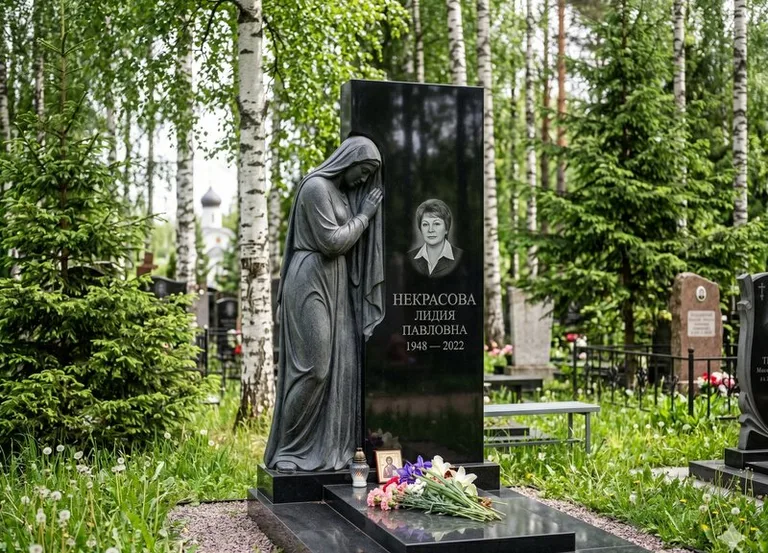 Гранитная фигура скорбящего мужчины у чёрной стелы в Краснодаре